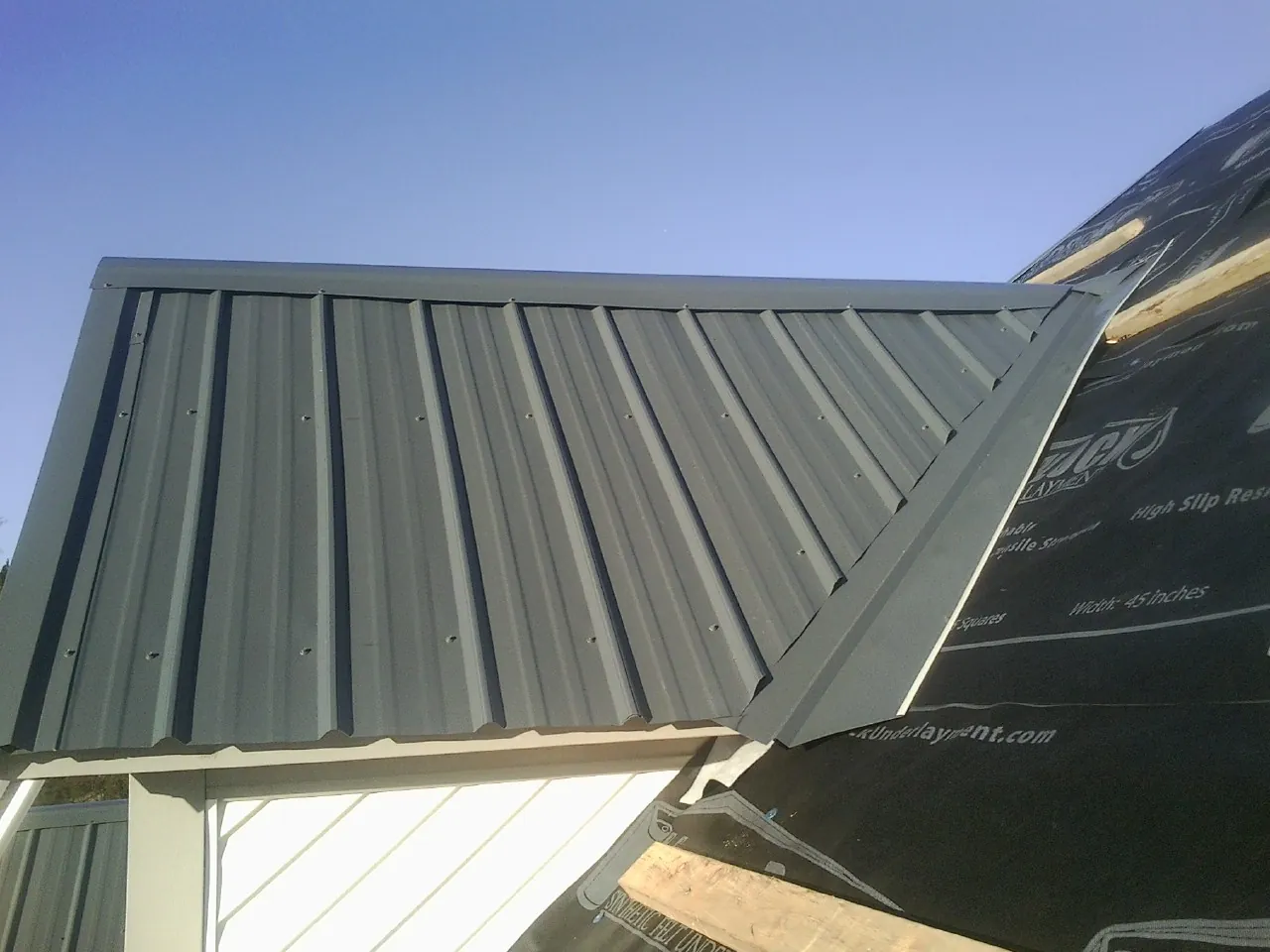 Gray metal roof panels going on over a garage gable in Chandler
