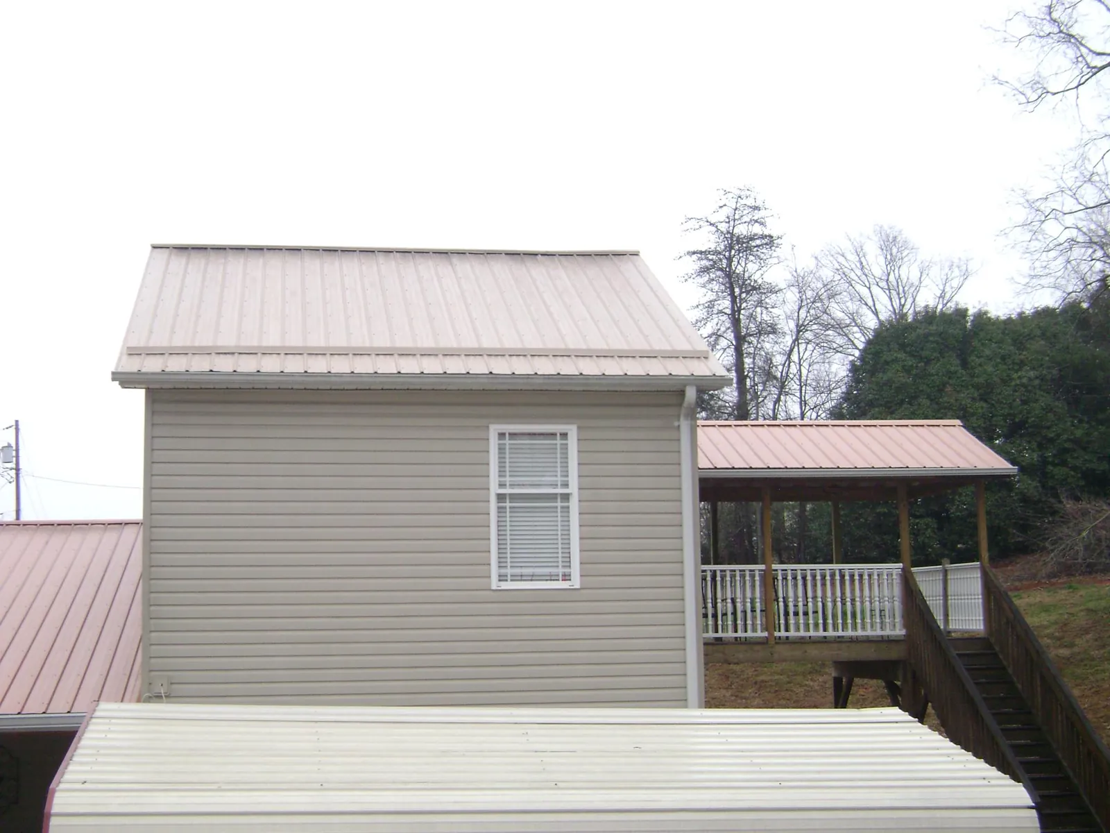 Tan metal roofs on a two story addition and attached porch, from a Roof Replacement job in Chandler
